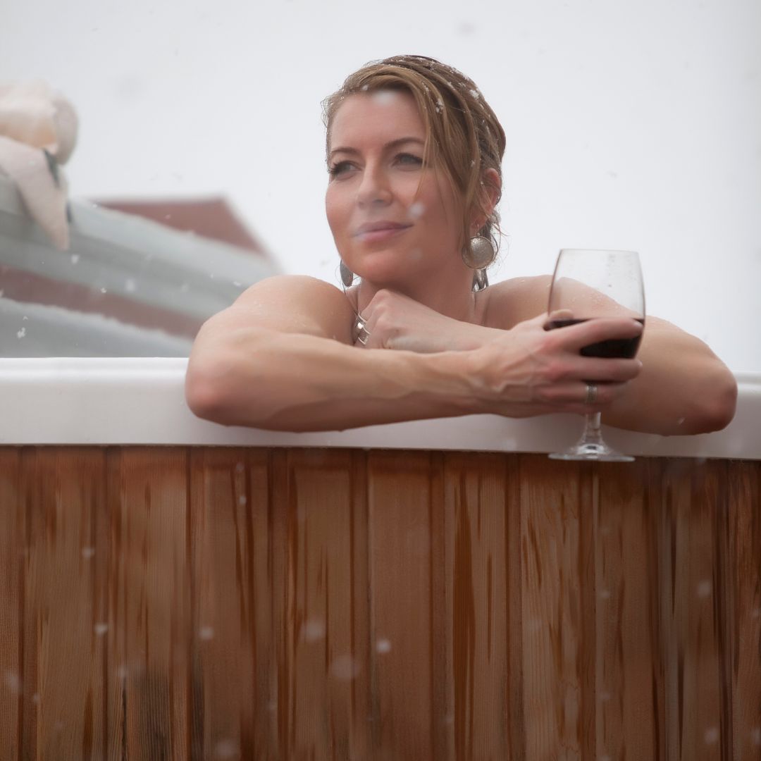 a woman sitting in a hot tub while it snows
