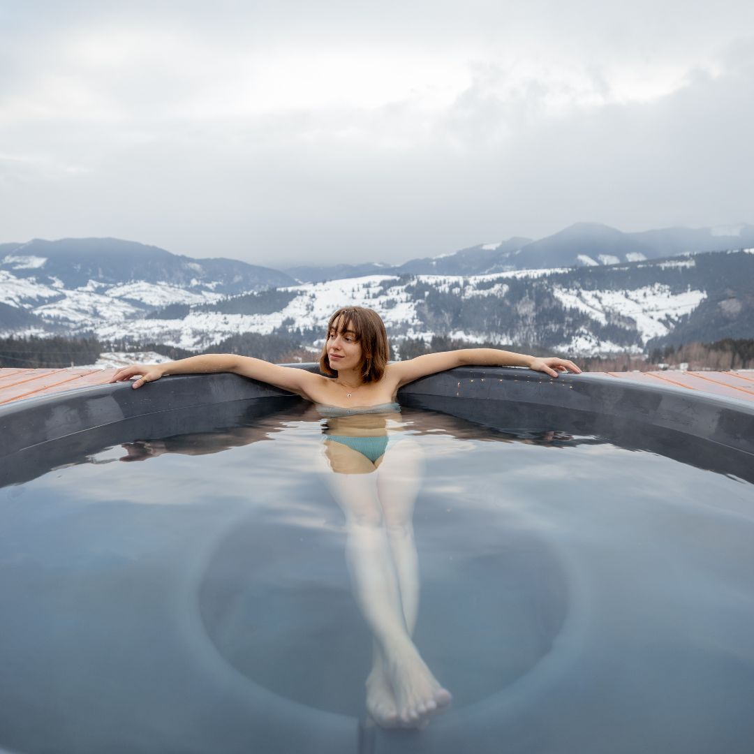 a person soaking in a hot tub in winter
